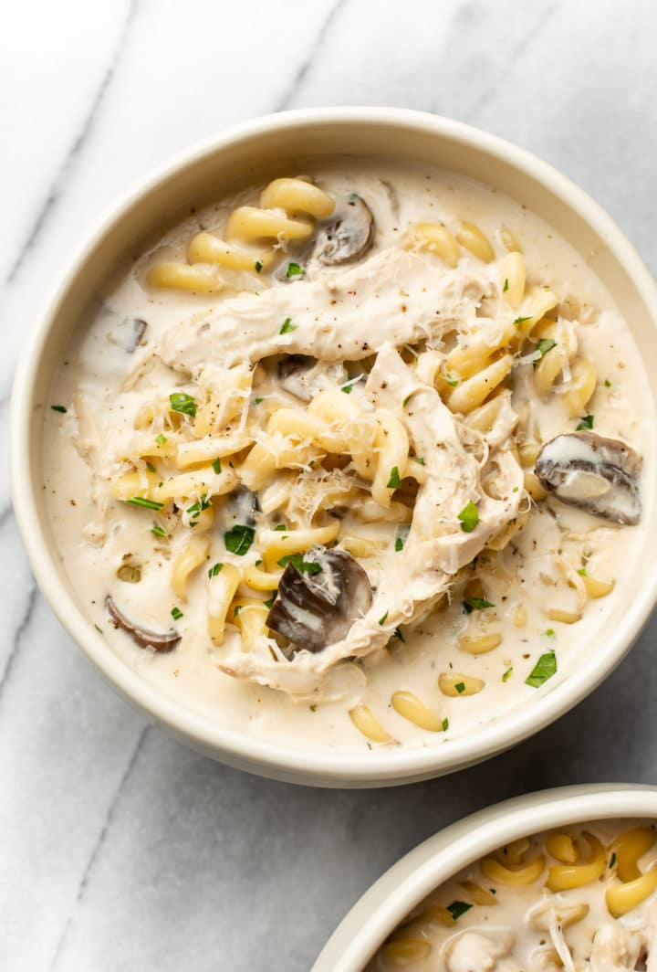 Chicken Tetrazzini Soup in two beige bowls on a marble background