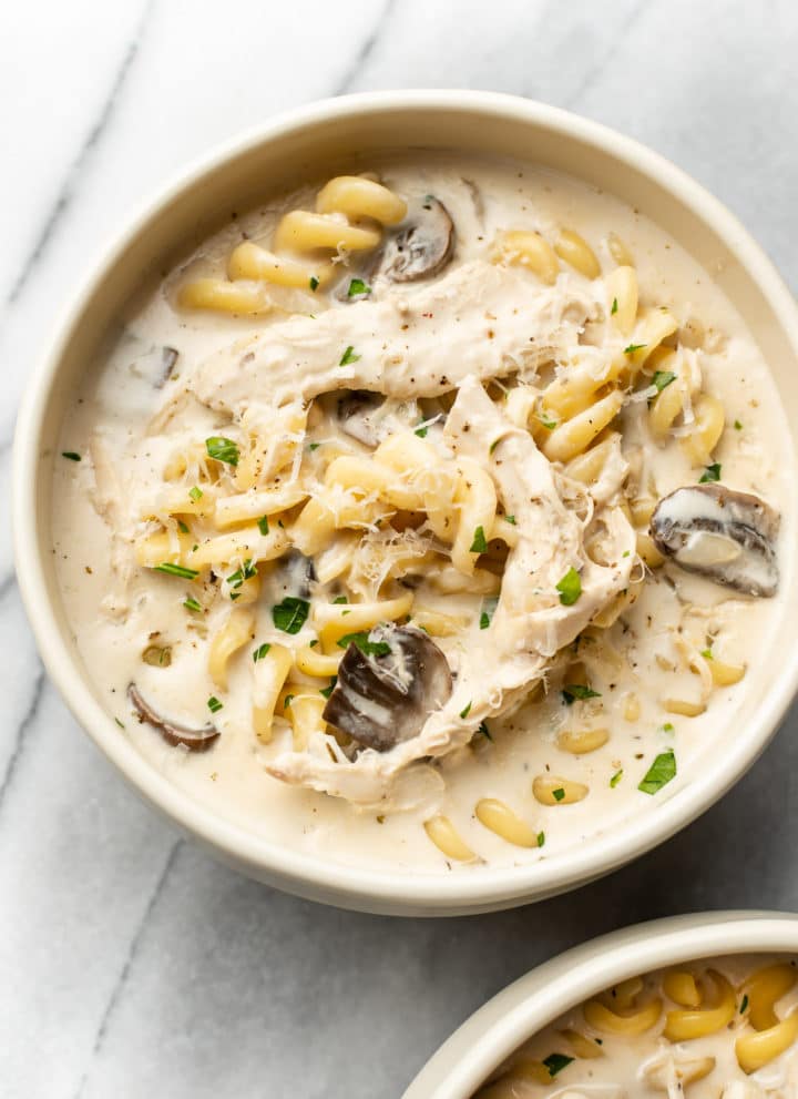 Chicken Tetrazzini Soup in two beige bowls on a marble background