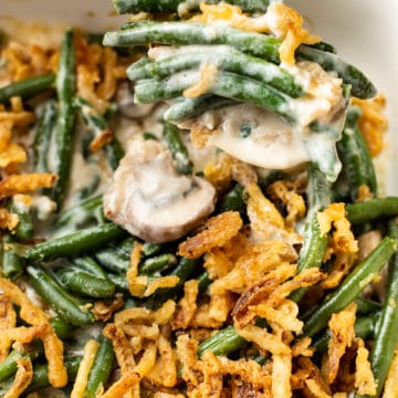 close-up of green bean casserole (from scratch) in a white baking dish with a spoonful being taken out