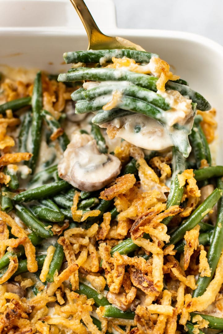 close-up of green bean casserole (from scratch) in a white baking dish with a spoonful being taken out