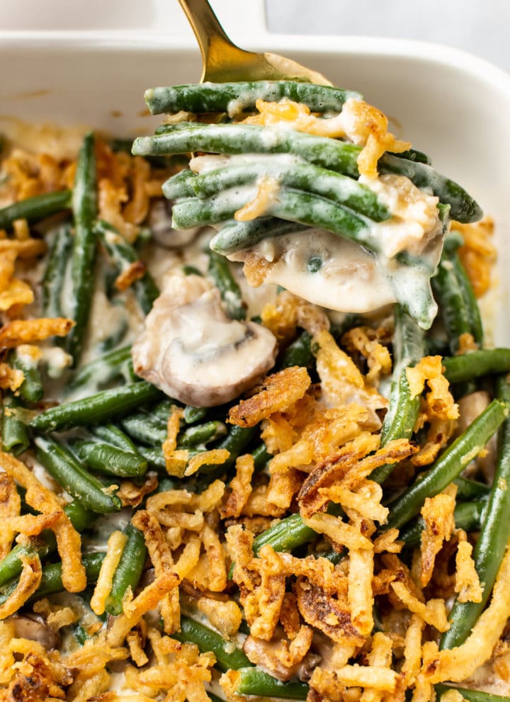 close-up of green bean casserole (from scratch) in a white baking dish with a spoonful being taken out