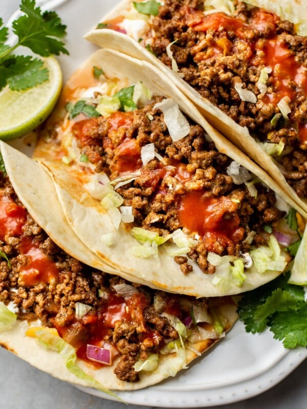 ground beef taco recipe (the best ground beef tacos loaded with toppings on a white plate)