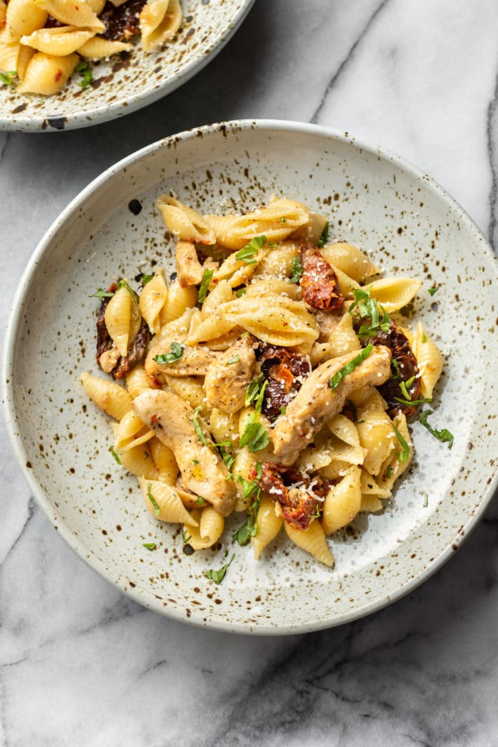 sun-dried tomato chicken pasta in two shallow bowls