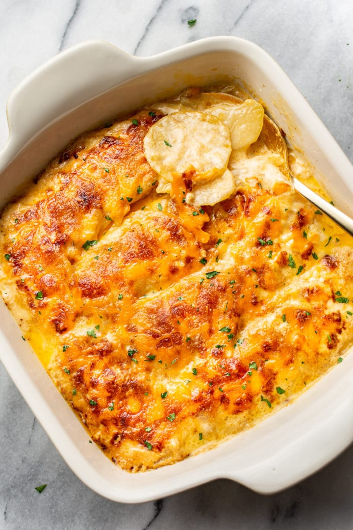 Cajun scalloped potatoes in a baking dish (with a spoonful being lifted out)