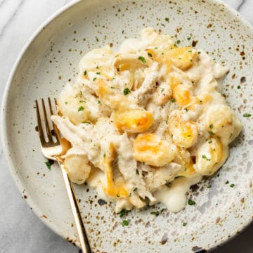 chicken alfredo baked gnocchi in a shallow bowl with a gold fork