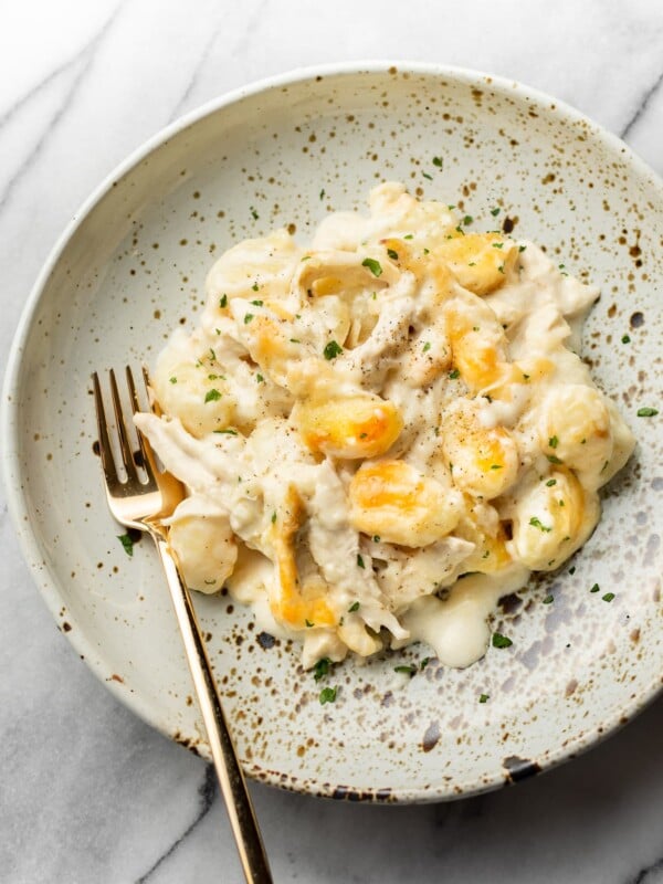 chicken alfredo baked gnocchi in a shallow bowl with a gold fork