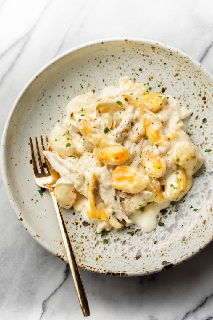 chicken alfredo baked gnocchi in a shallow bowl with a gold fork