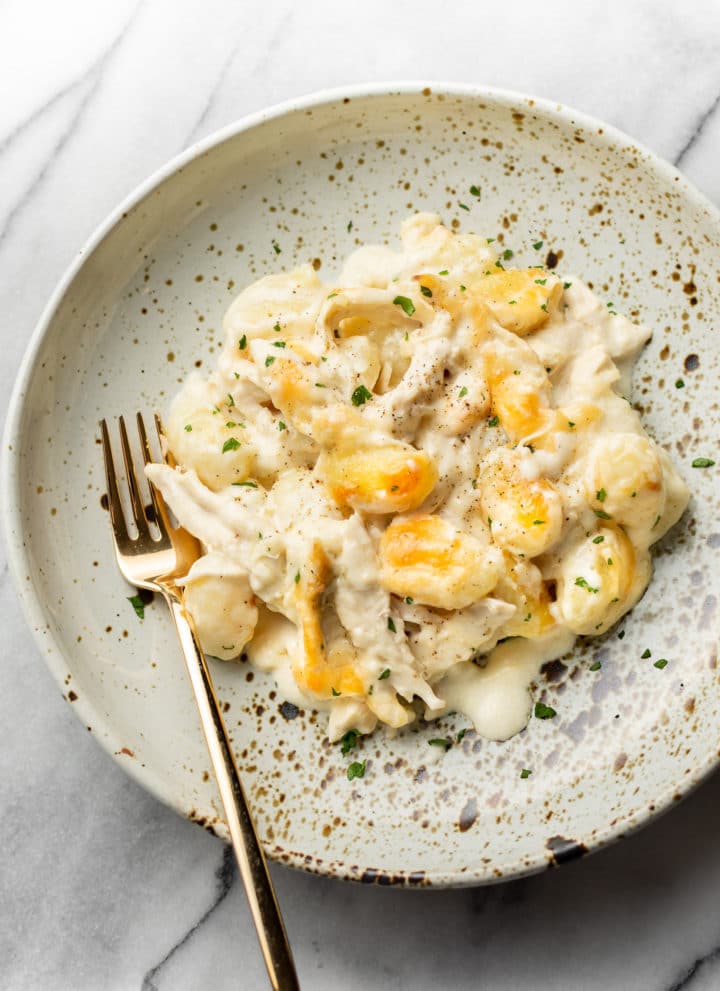 chicken alfredo baked gnocchi in a shallow bowl with a gold fork
