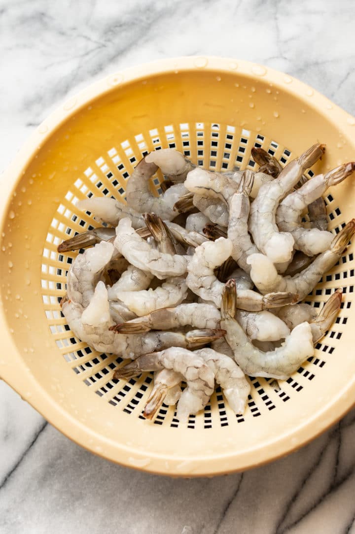 uncooked shrimp in a colander