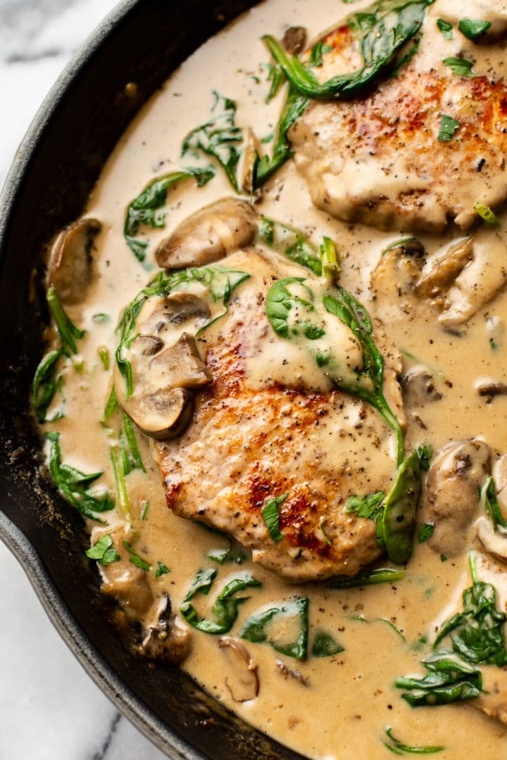 close-up of creamy mushroom spinach pork chops in a skillet