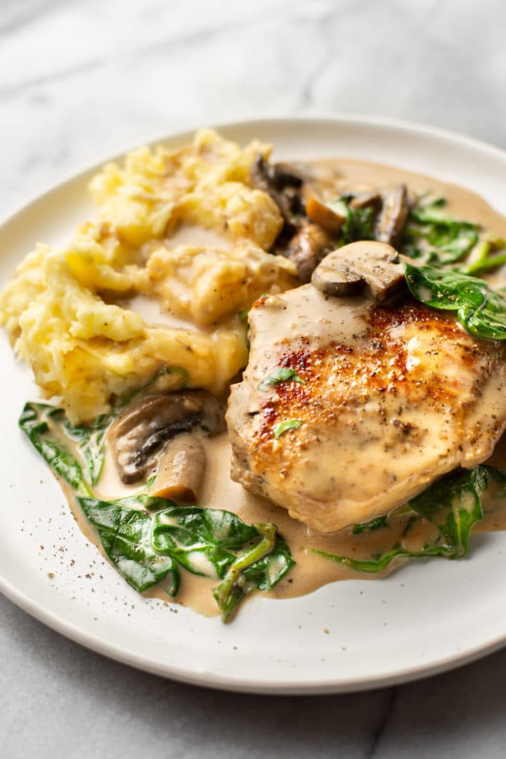 creamy pork chops with spinach and mushrooms on a plate with mashed potatoes