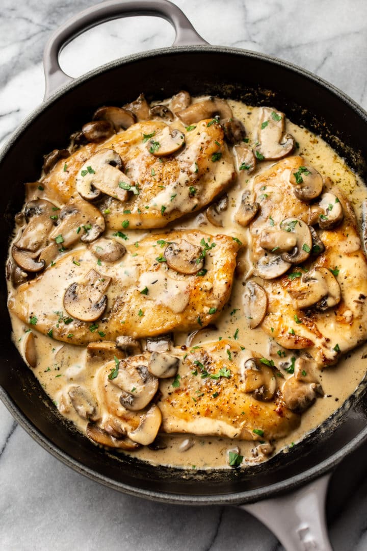 creamy white wine mushroom chicken in a skillet on a marble background