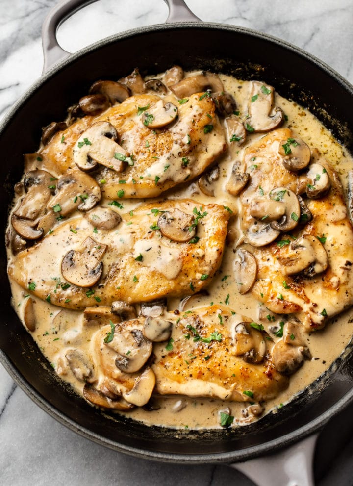 creamy white wine mushroom chicken in a skillet on a marble background