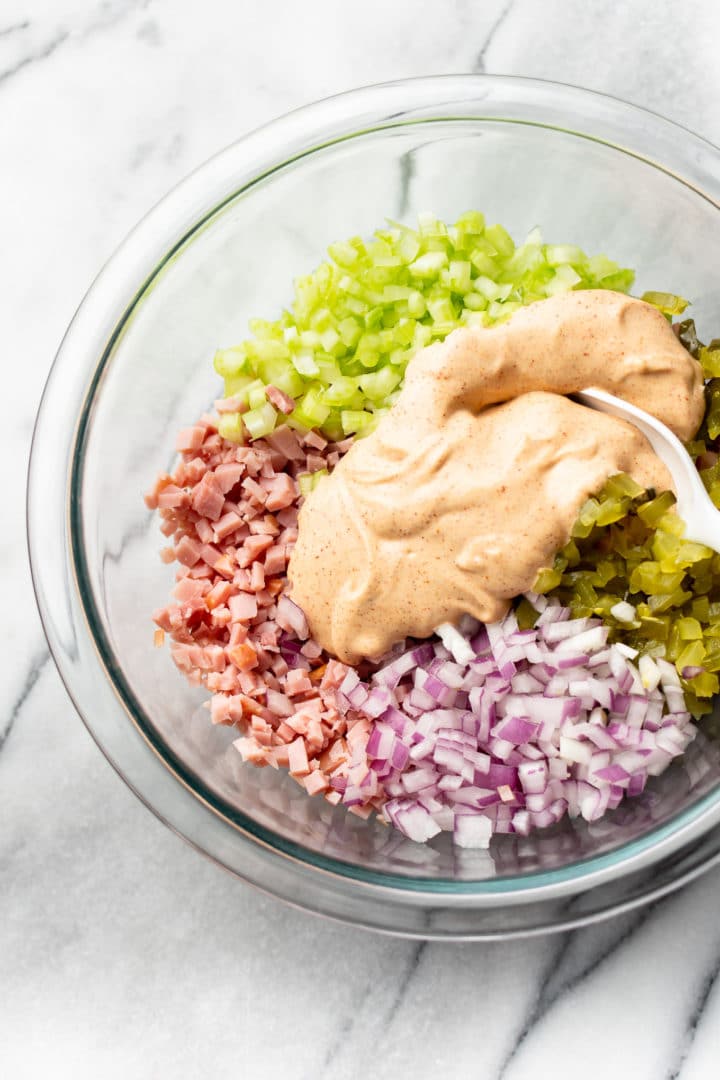 ham salad ingredients ready to be mixed in a glass prep bowl