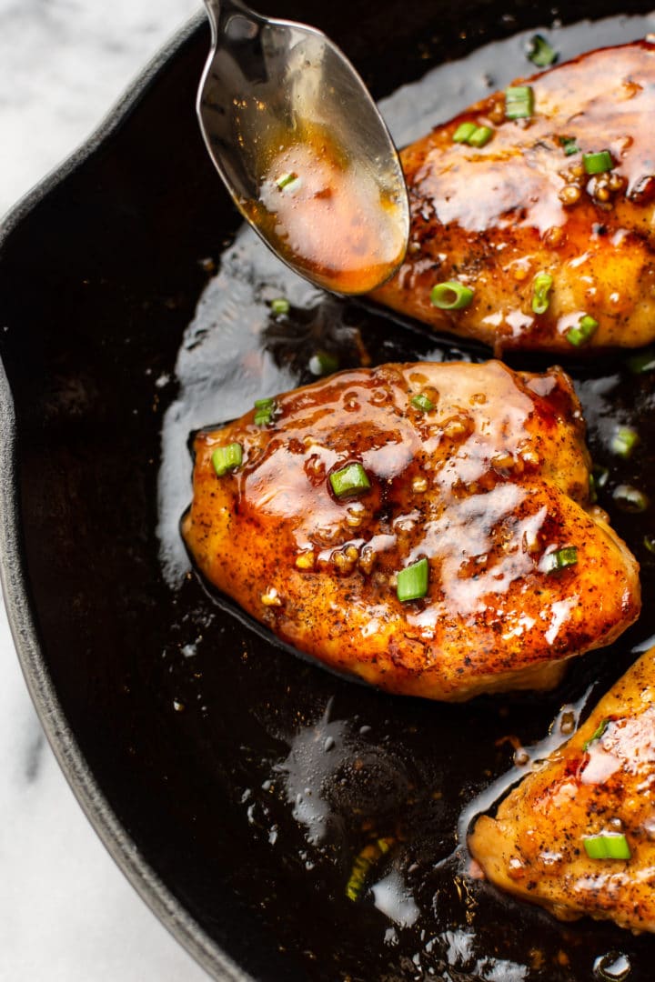 close-up of honey garlic chicken (in a skillet with a spoonful of sauce)
