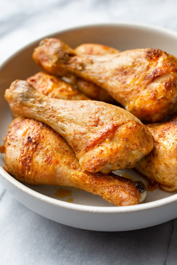 close-up of baked chicken legs (drumsticks) stacked in a bowl