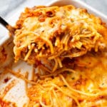 close-up of baked spaghetti in a casserole dish being lifted out with a spatula