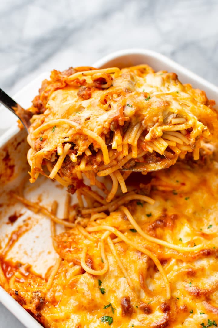 close-up of baked spaghetti in a casserole dish being lifted out with a spatula