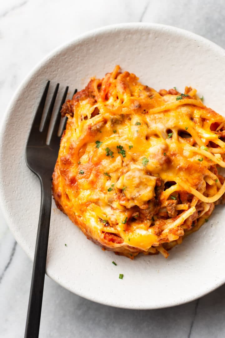 baked spaghetti in a shallow bowl with a fork