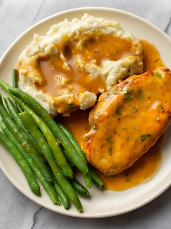 chicken and gravy with mashed potatoes and green beans on a plate