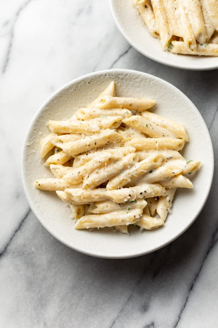 creamy garlic penne pasta in two white bowls