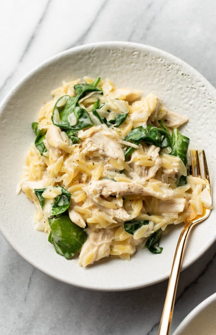 lemon chicken orzo in a shallow bowl with a golden fork