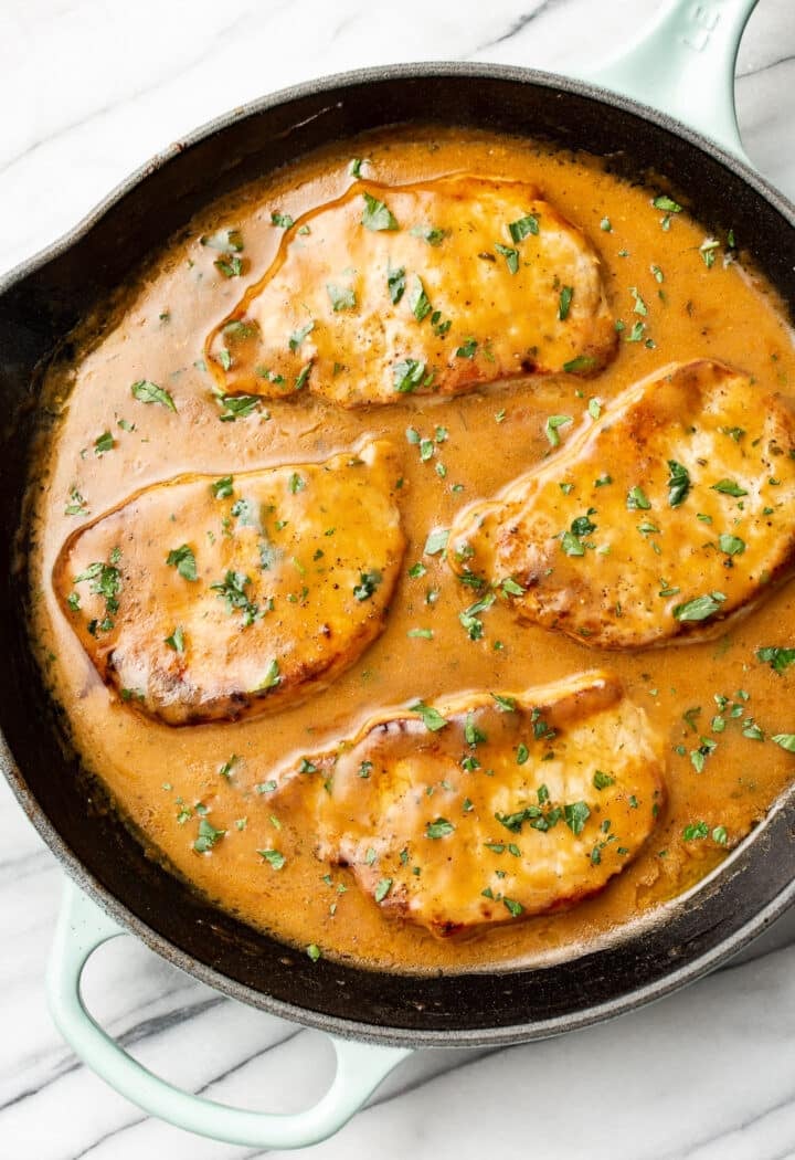 four pork chops with a ranch sauce in a cast iron skillet