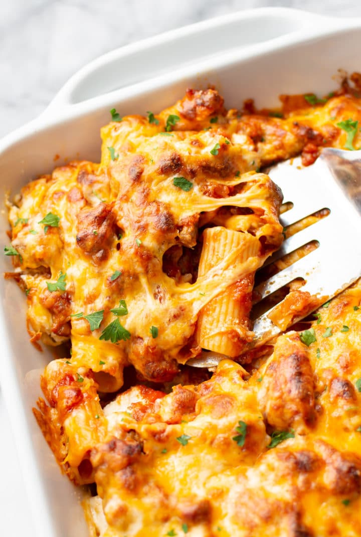 close-up of the best baked rigatoni in a casserole dish (portion is being lifted out with a spatula)