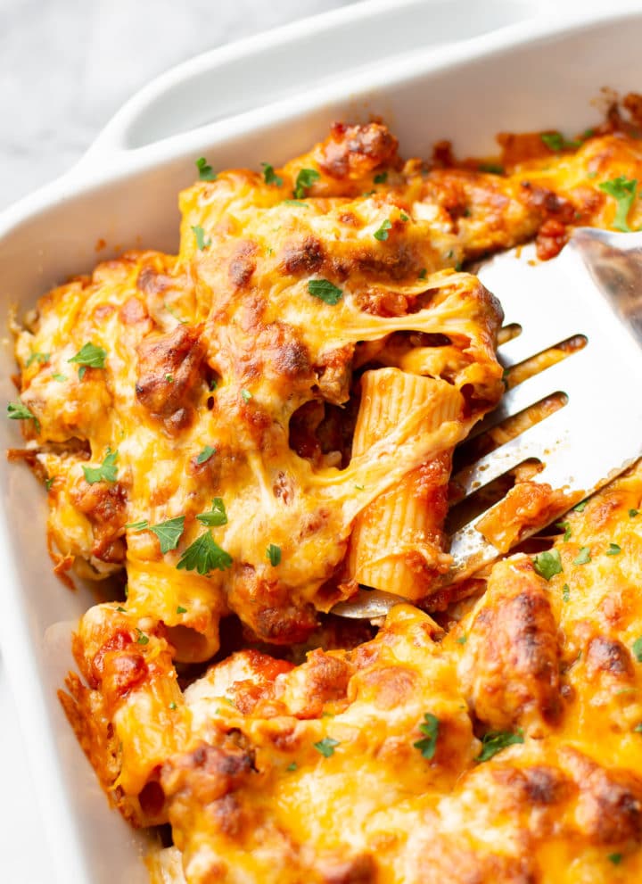 close-up of the best baked rigatoni in a casserole dish (portion is being lifted out with a spatula)