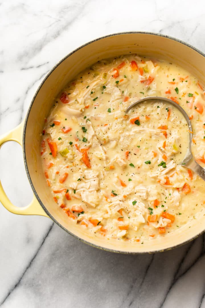 close-up of creamy chicken rice soup in a pot with a ladle