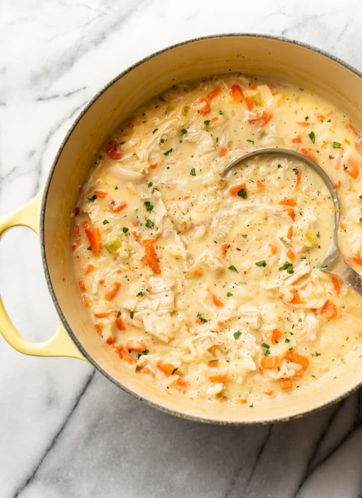 close-up of creamy chicken rice soup in a pot with a ladle