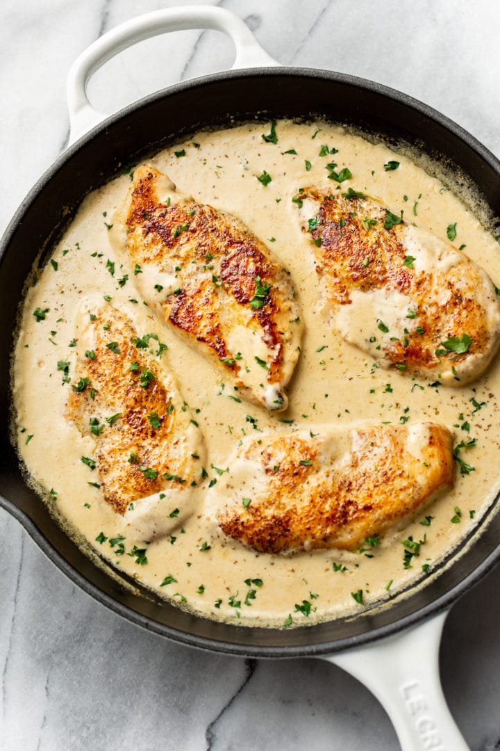 creamy parmesan chicken breasts in a skillet