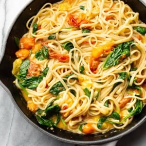 garlic butter pasta with fresh tomatoes tossed with linguine in a skillet