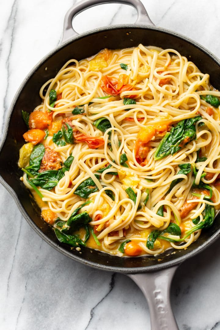 garlic butter pasta with fresh tomatoes tossed with linguine in a skillet