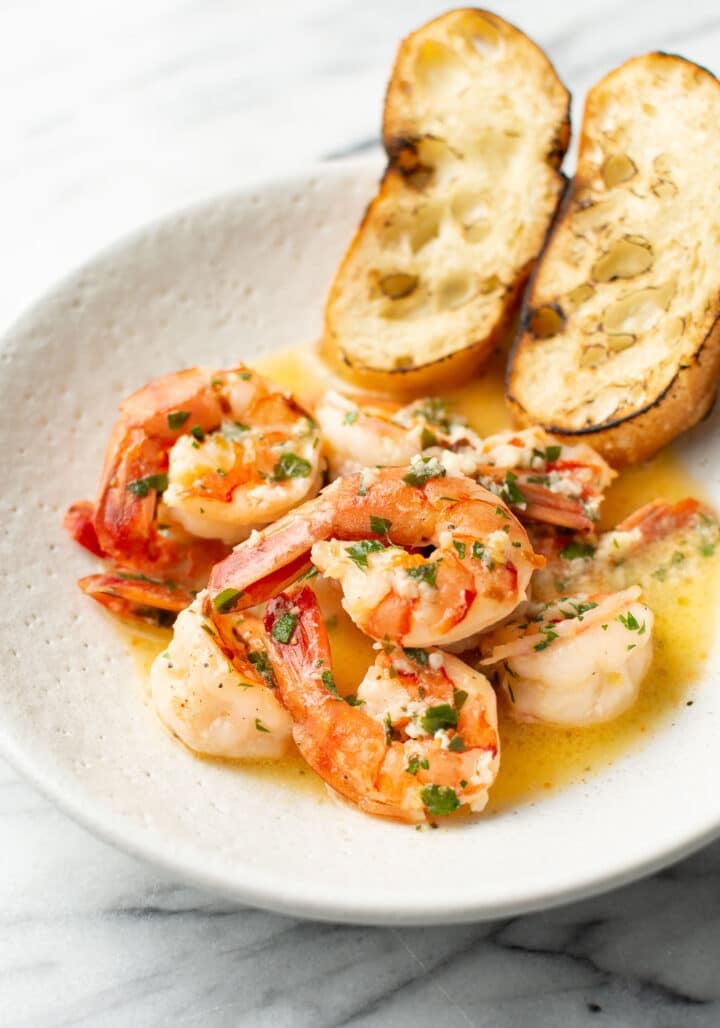 a plate of shrimp scampi with toasted baguette