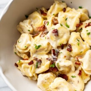 close-up of creamy ranch tortellini with bacon in a white bowl