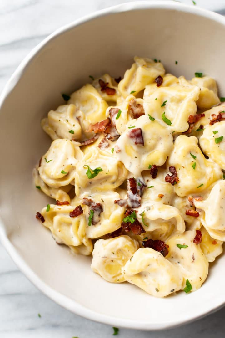 close-up of creamy ranch tortellini with bacon in a white bowl