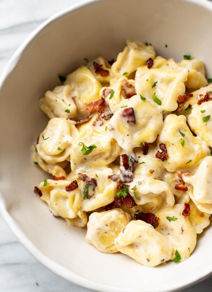 close-up of creamy ranch tortellini with bacon in a white bowl