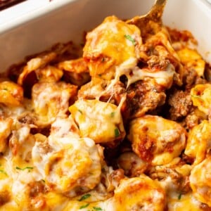 close-up of a spoonful of cheesy baked tortellini in a Staub baking dish