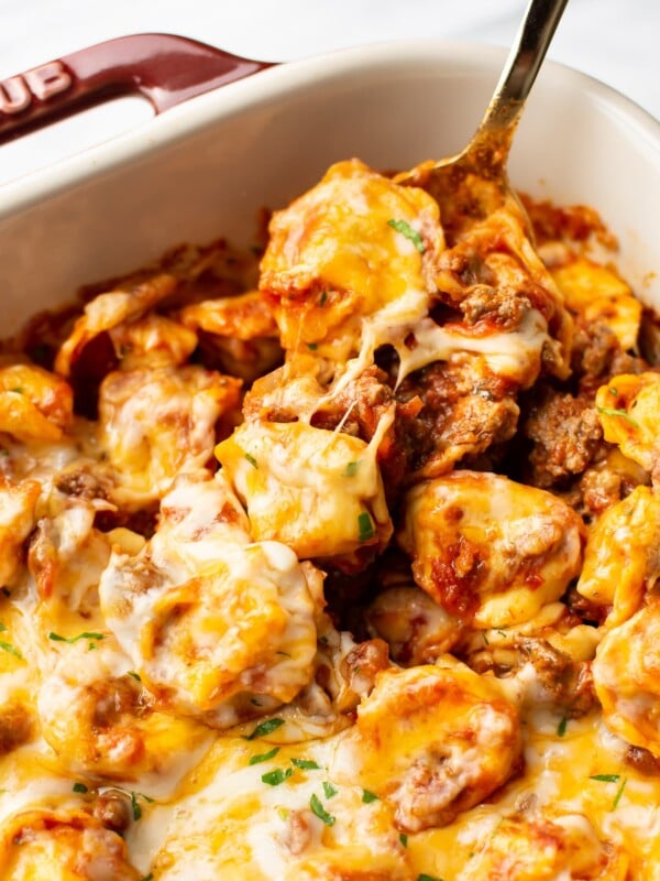 close-up of a spoonful of cheesy baked tortellini in a Staub baking dish