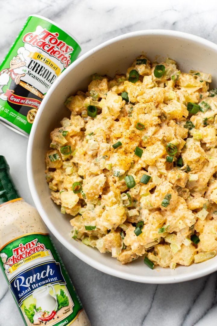 Creole ranch potato salad in a serving bowl with Tony Chachere's Original Creole Seasoning shaker container and Tony's Ranch Dressing bottle