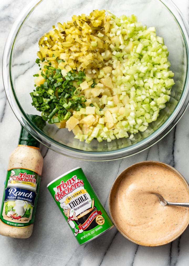 prep bowl with potato salad ingredients, small bowl with dressing, and Tony Chachere's Original Creole Seasoning container and Tony's Ranch Dressing bottle