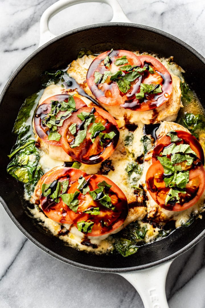 caprese chicken in a skillet on marble background