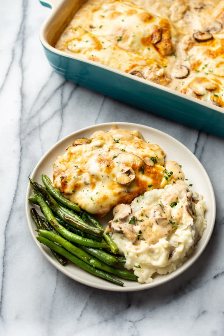 Chicken Gloria (creamy chicken casserole with mushrooms) plated with the casserole dish in the background