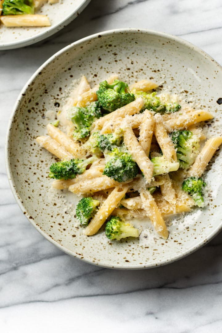 creamy broccoli pasta in two shallow bowls