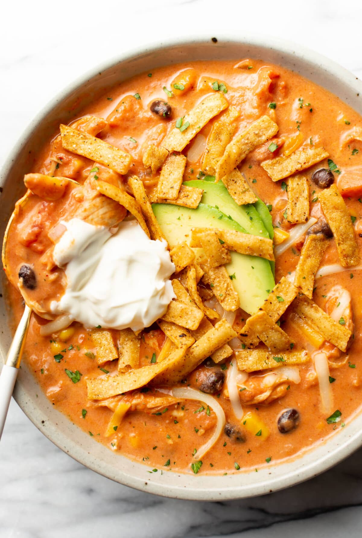 a bowl of creamy chicken tortilla soup with a spoon