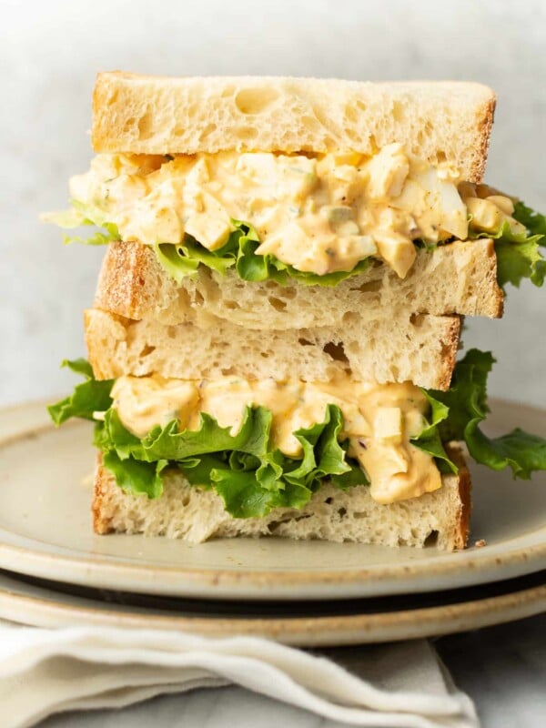 two egg salad sandwiches stacked on a plate