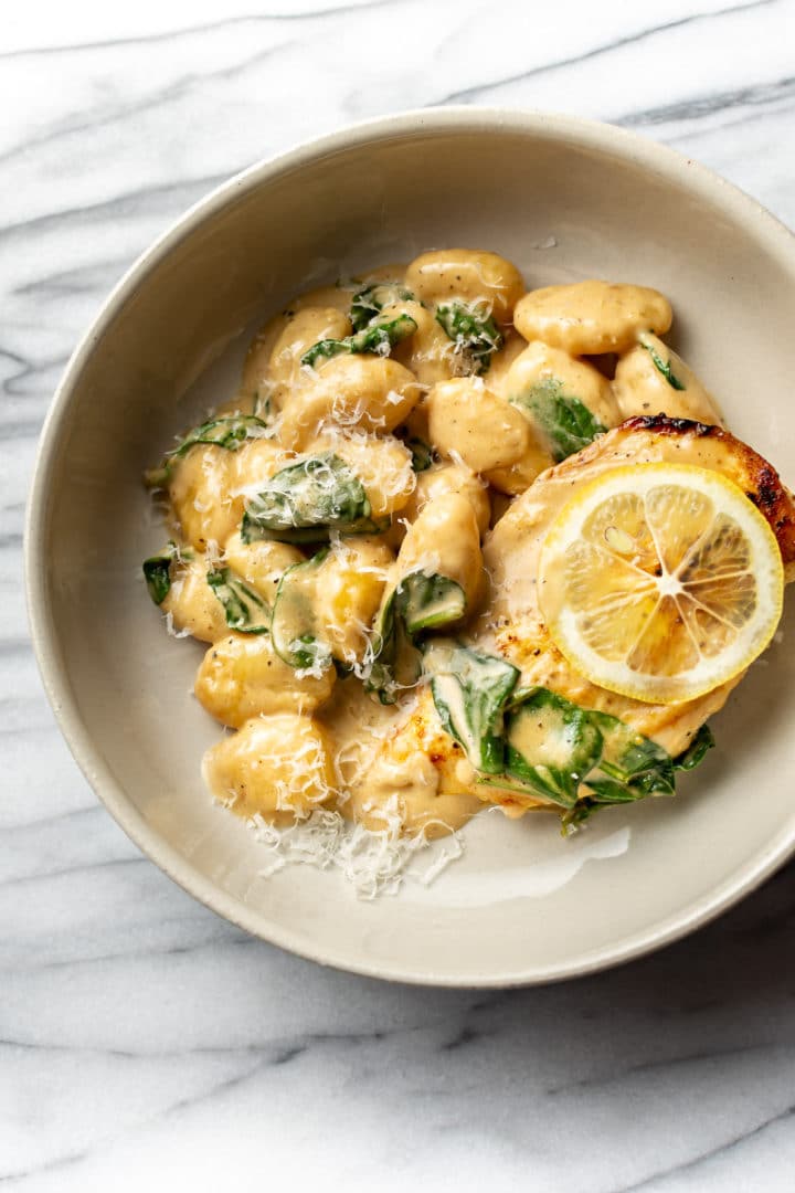 lemon chicken gnocchi in a shallow bowl on a marble background