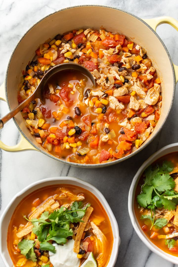 Mexican chicken soup in a yellow pot, plus two garnished bowls of the soup