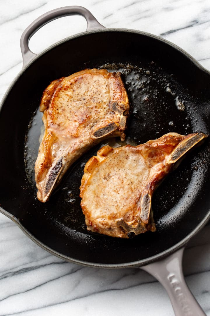 pan seared pork chops in a gray Le Creuset skillet